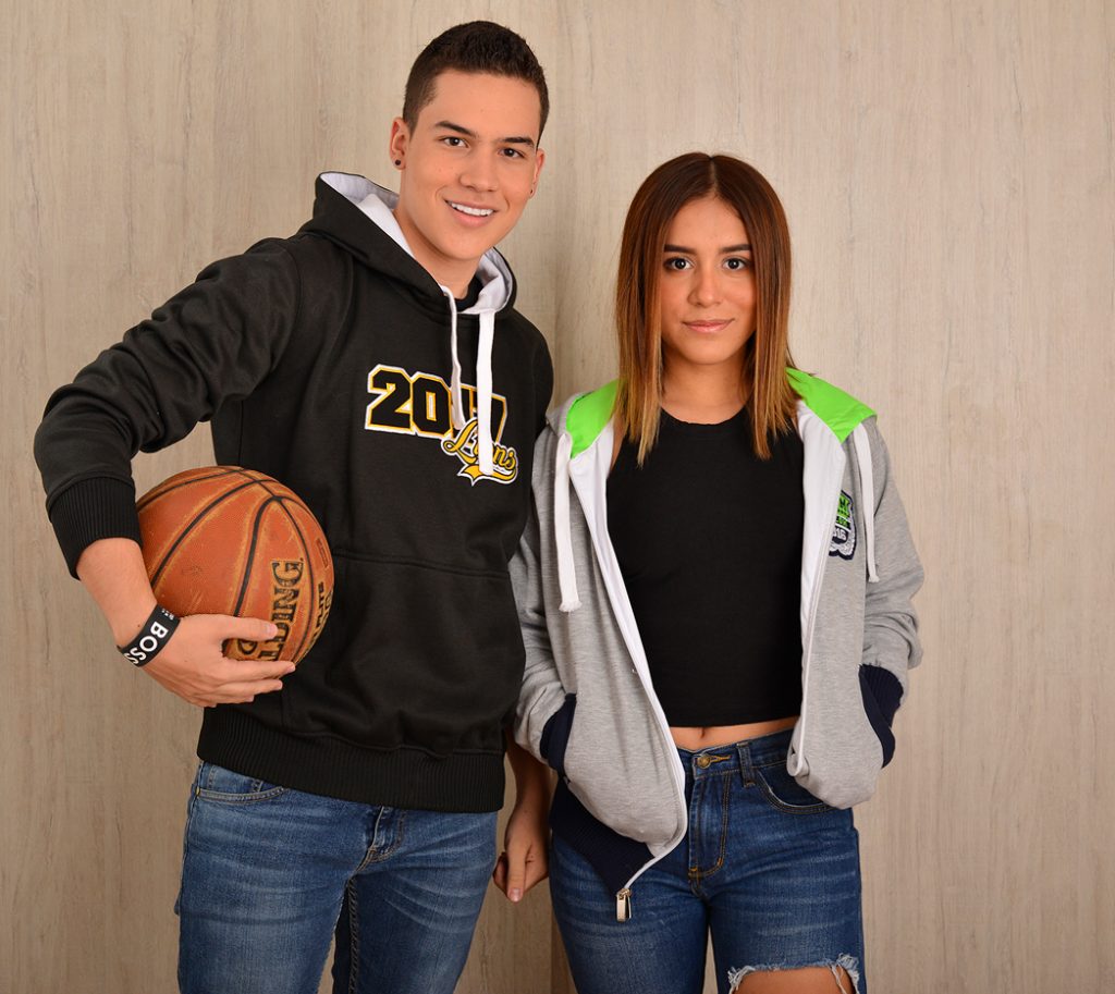 Dos personas con sudaderas con capucha junto a un balón de baloncesto.
