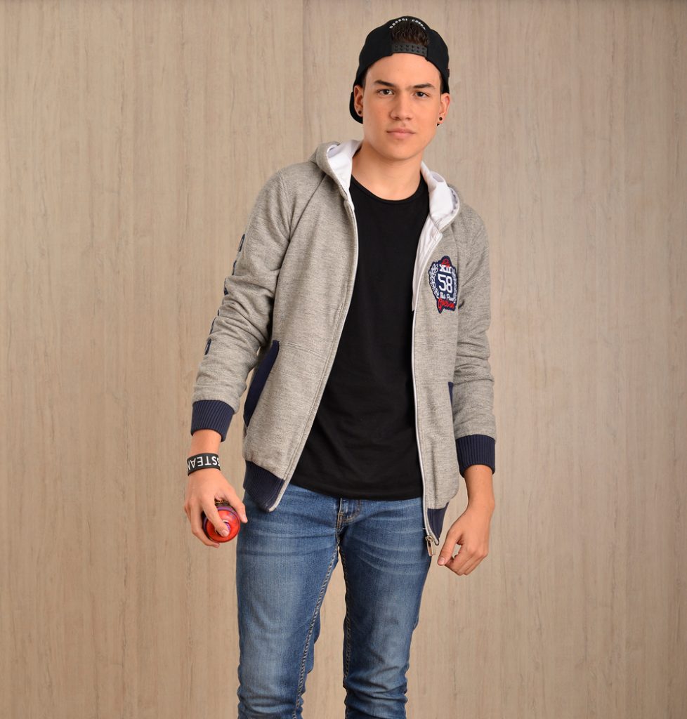 Persona con sudadera gris con capucha, parche numerado y balón deportivo.