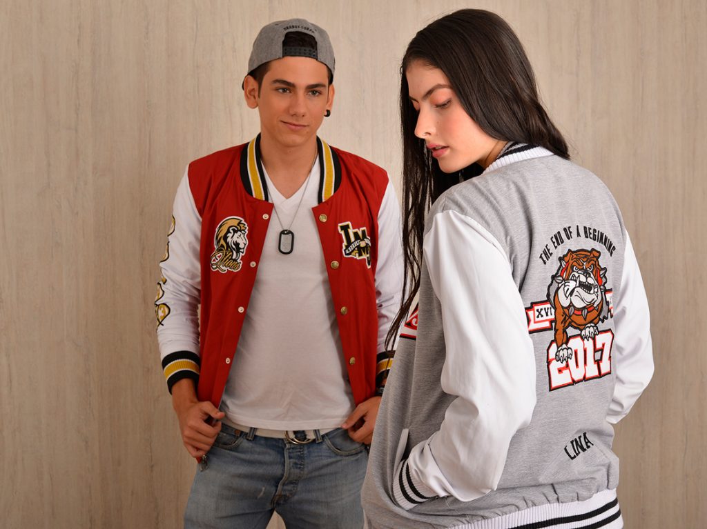 Dos personas muestran el frente y la espalda de chaquetas varsity con gráficos.