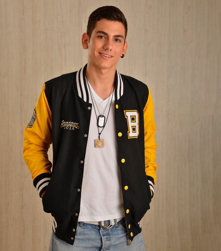 Persona con chaqueta varsity negra y amarilla, con letra y parches.