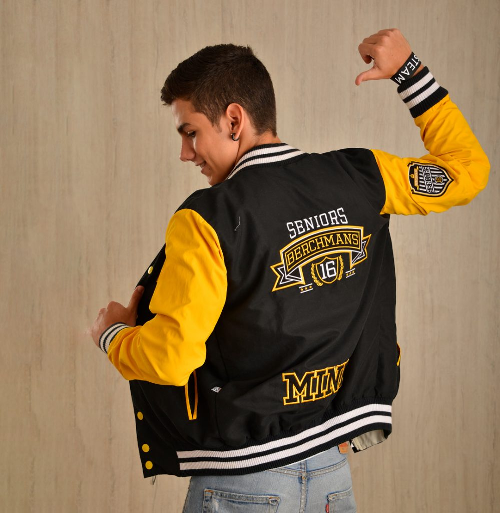 Vista posterior de una chaqueta varsity negra y amarilla con gráfico bordado.