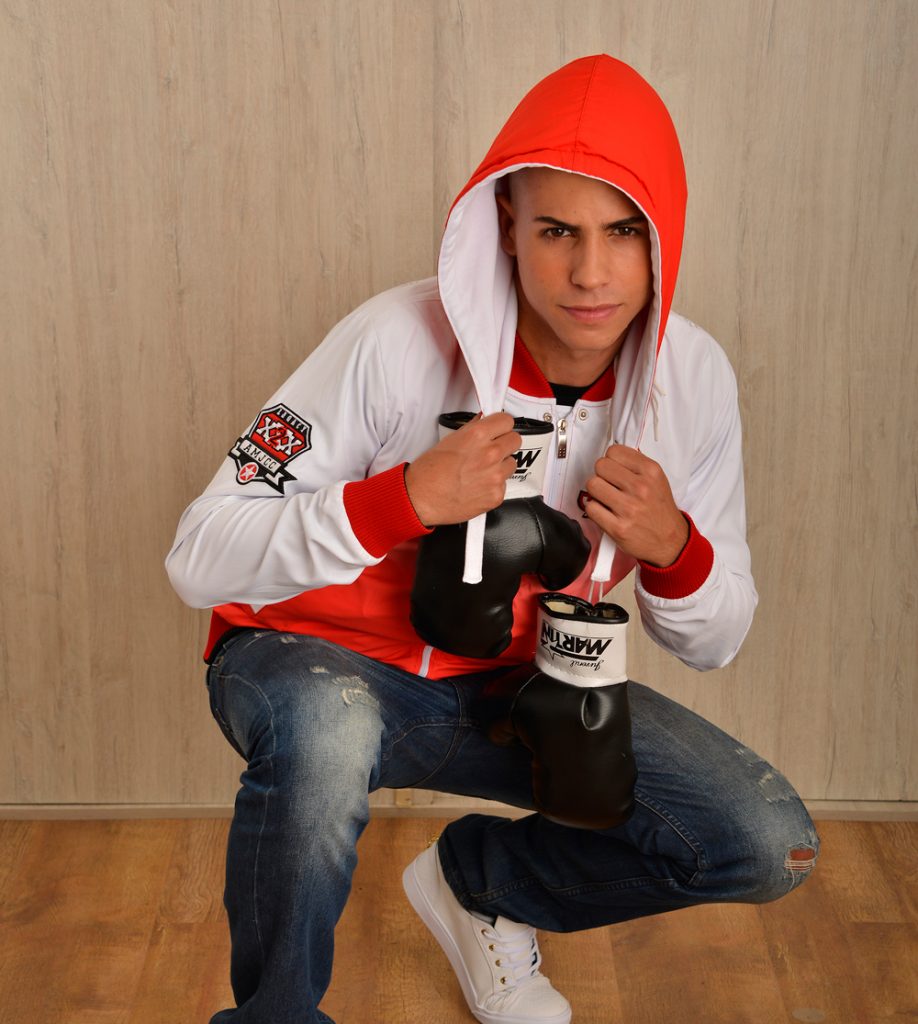 Persona sentada con chaqueta blanca y roja con capucha y guantes de boxeo.